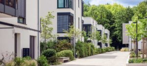 Modernes Mehrfamilienhaus der FÖFA mit Briefkastenanlage, gepflegter Außenanlage und Fußweg zwischen den Gebäuden