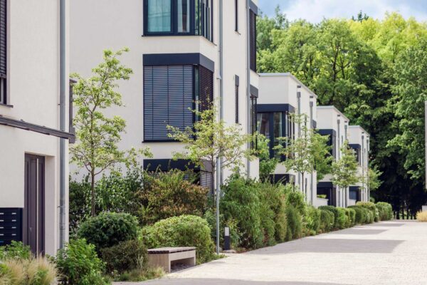 Modernes Mehrfamilienhaus der FÖFA mit Briefkastenanlage, gepflegter Außenanlage und Fußweg zwischen den Gebäuden