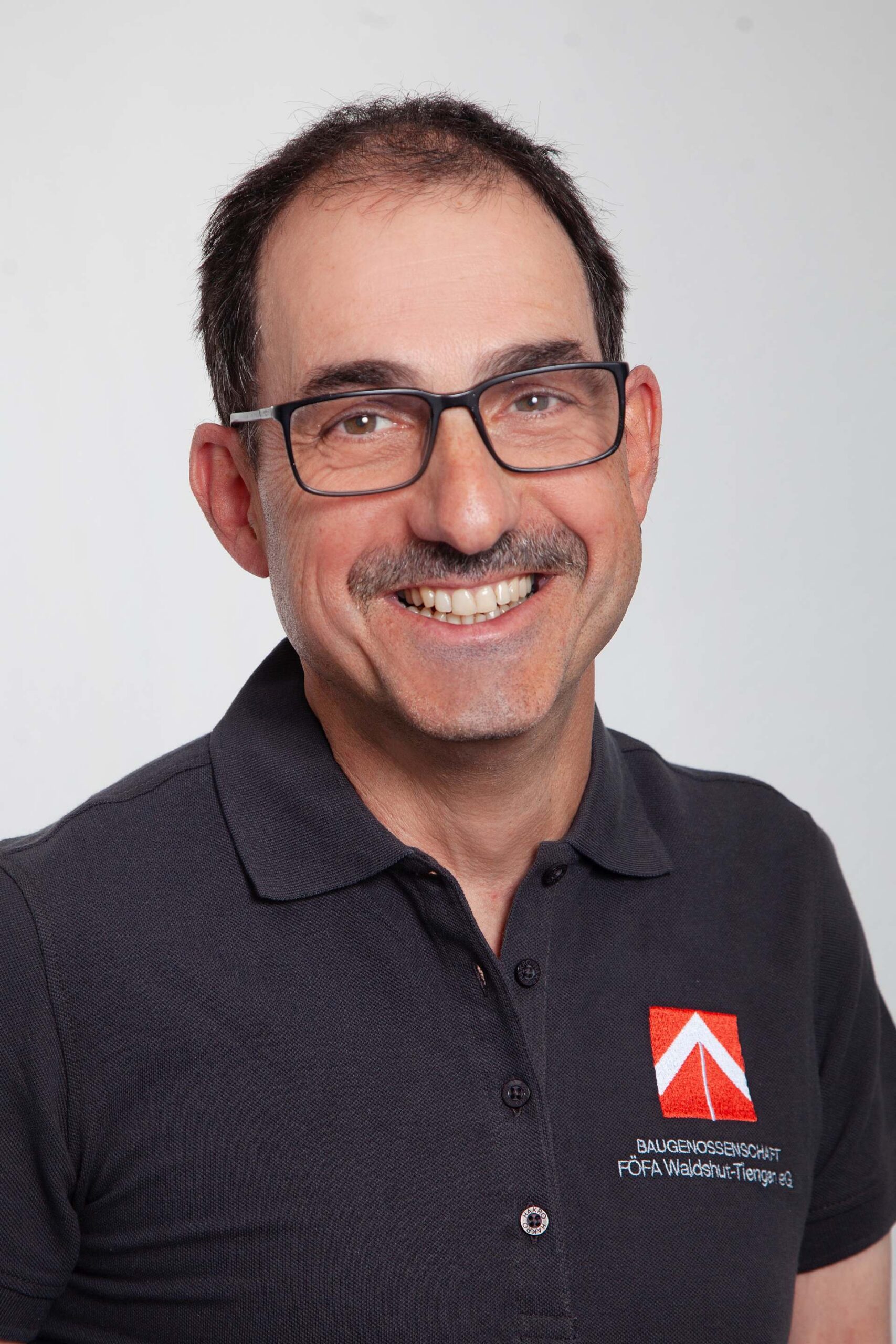 Porträt eines FÖFA Mitarbeiters mit Brille und Schnurrbart im FÖFA Poloshirt
